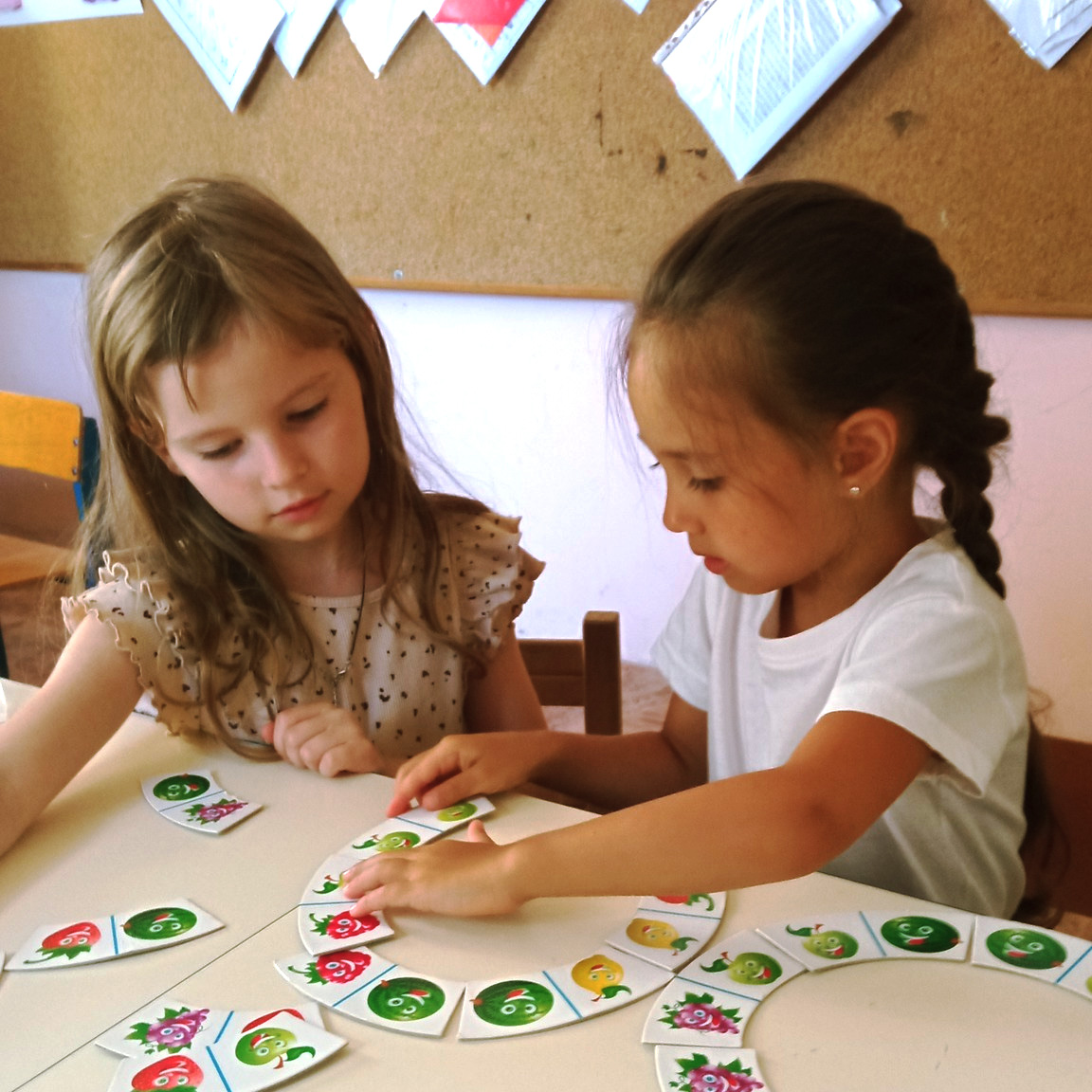 Două fete rezolvă un joc de potrivire cu piese ilustrate