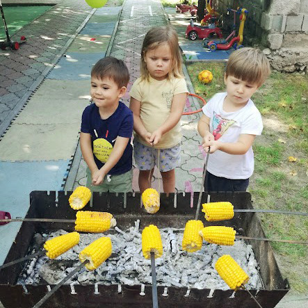 Copii prăjesc porumb pe jar, activitate în aer liber